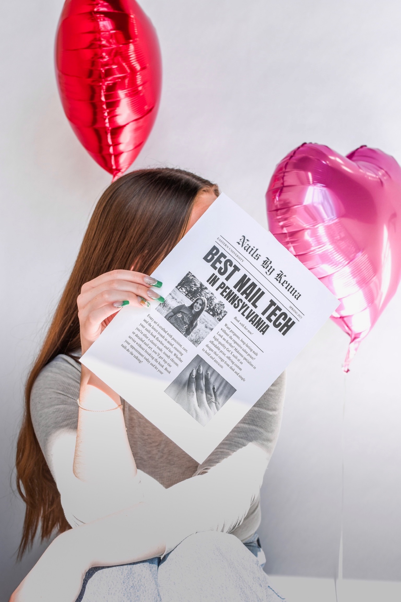 Makenna holding a 'Best Nail Tech in Pennsylvania' newspaper with heart balloons